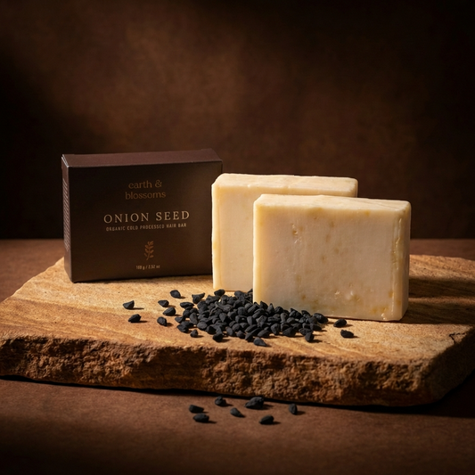 Three bars of soap and a box labeled 'Onion Seed' on a wooden surface with a dark background.