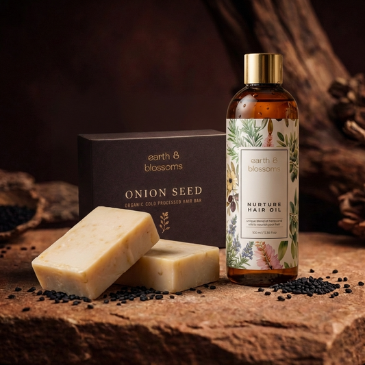 Bottle of Earth & Blossoms onion seed hair oil with soap bars and packaging on a wooden surface.