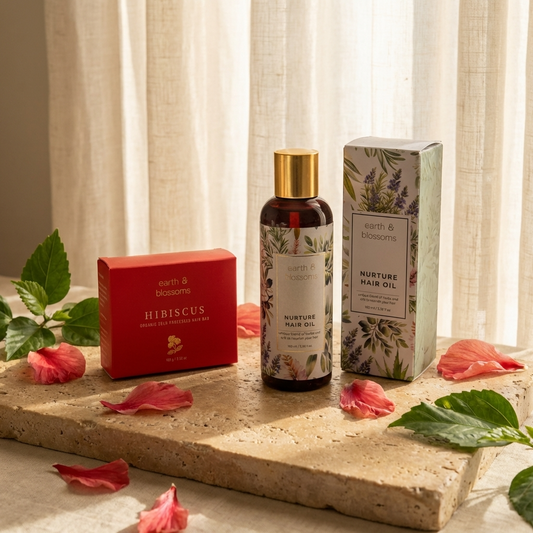 Nurture hair oil bottle with packaging on a stone surface with flowers and leaves.