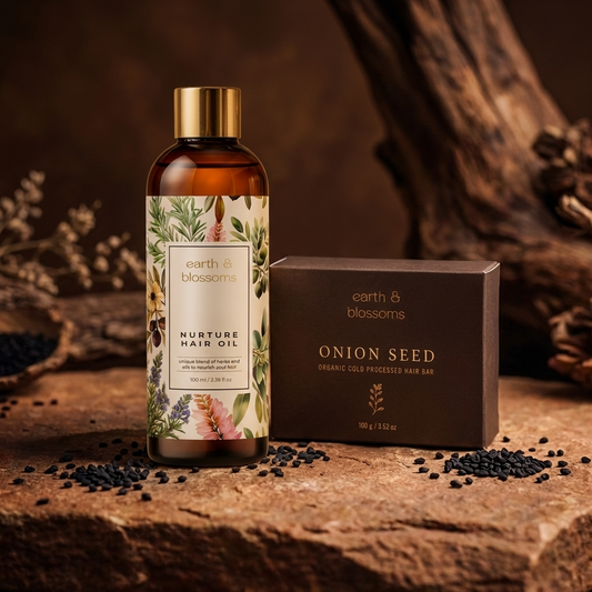 Hair oil bottle and onion seed bar from 'earth & blossoms' on a wooden surface with natural elements.